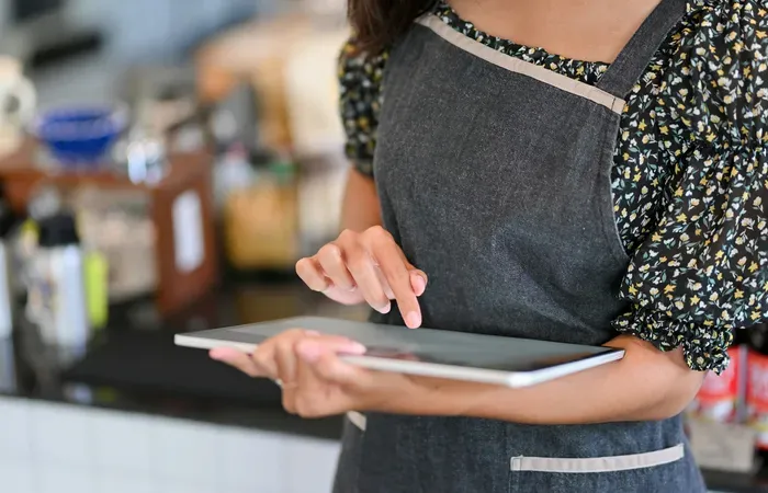 Female barista managing orders on a digital tablet inside her coffee shop listed on towndirectorysource.net